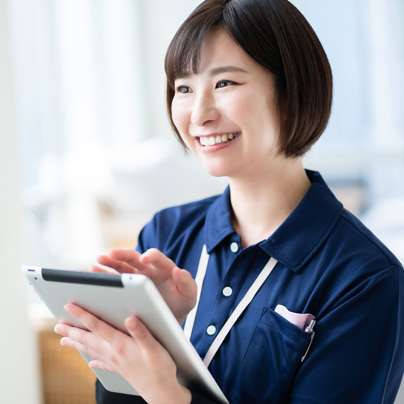 サービス提供者の女性スタッフが笑顔でタブレットを操作